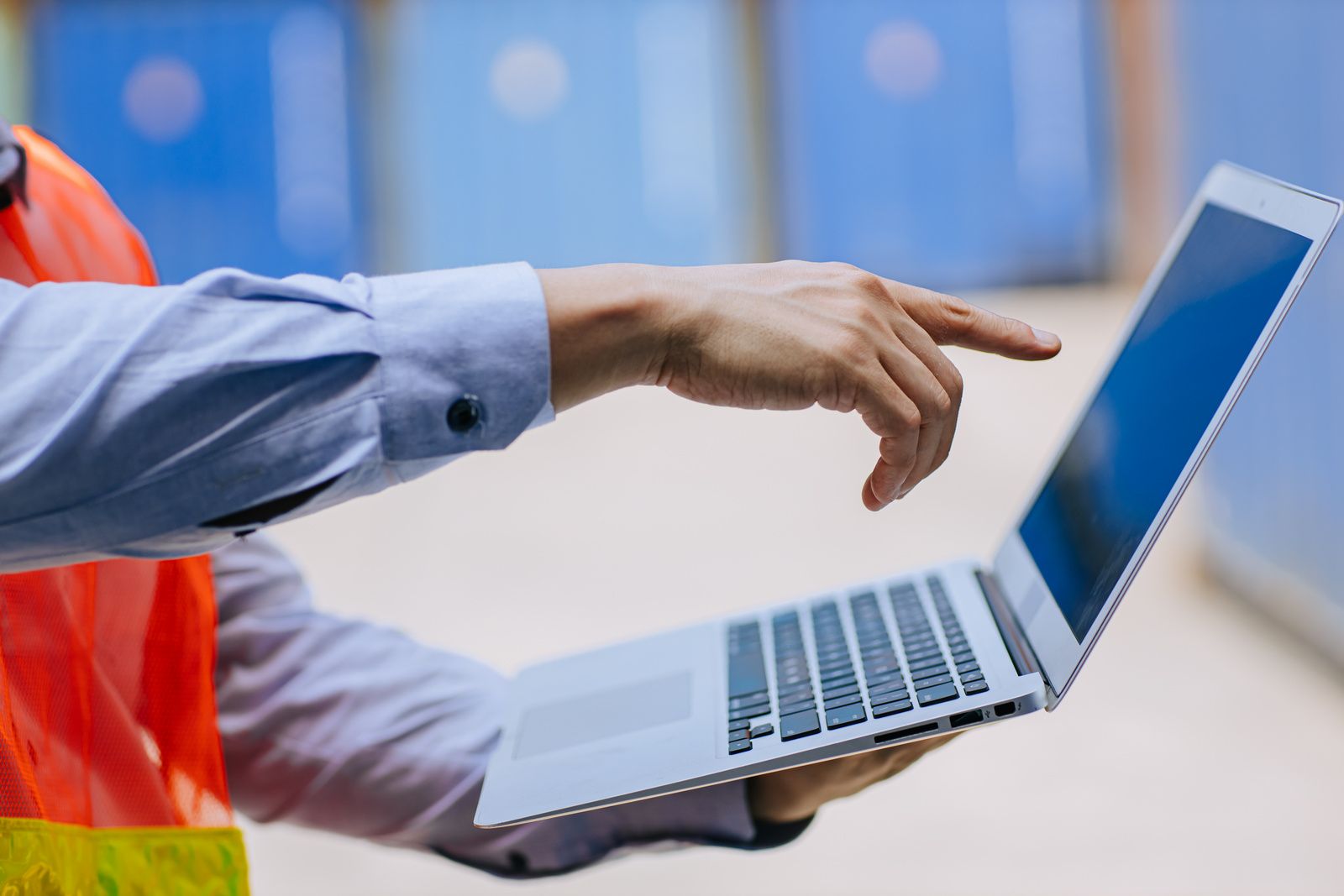 Láthatósági mellényes munkavállaló laptopon dolgozik
